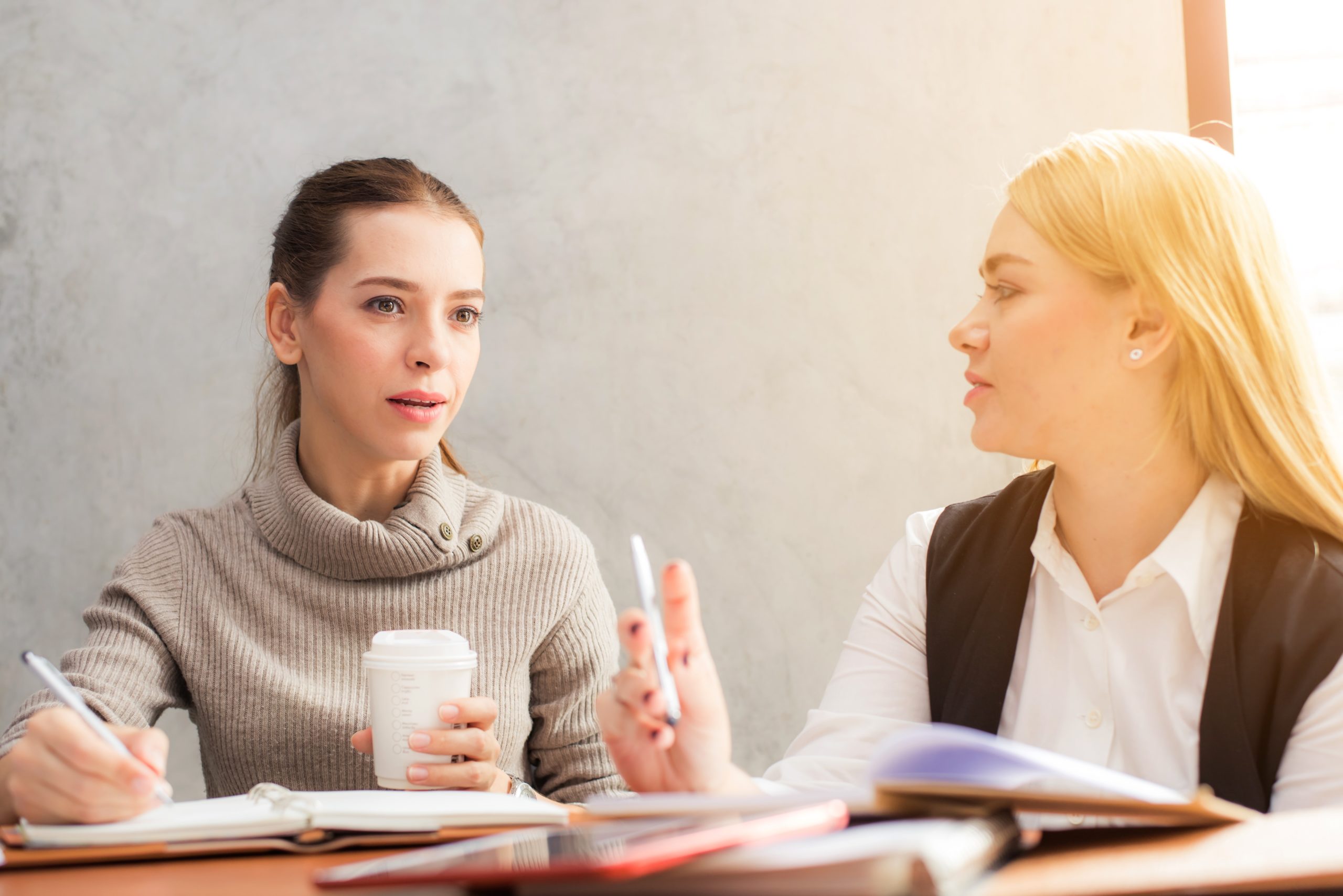 Two women in conversation with notebooks
