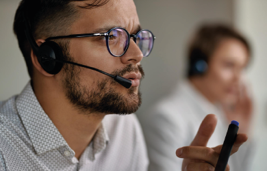 Young customer service representative explaining something while communicating with clients from call center office